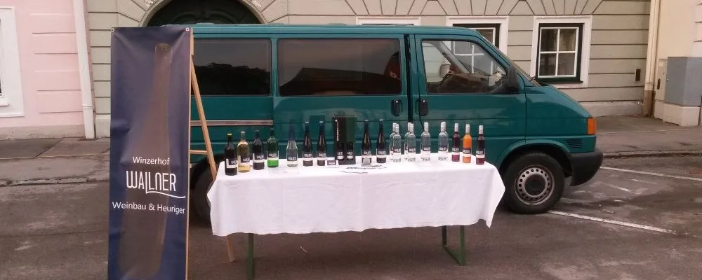 Verkaufsstand mit Flaschen auf einem Tisch, daneben ein Roll-up mit dem Schriftzug Winzerhof Wallner