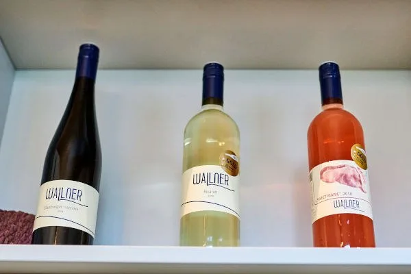 Drei Flaschen vom Winzerhof Wallner in einer hellen Wandnische