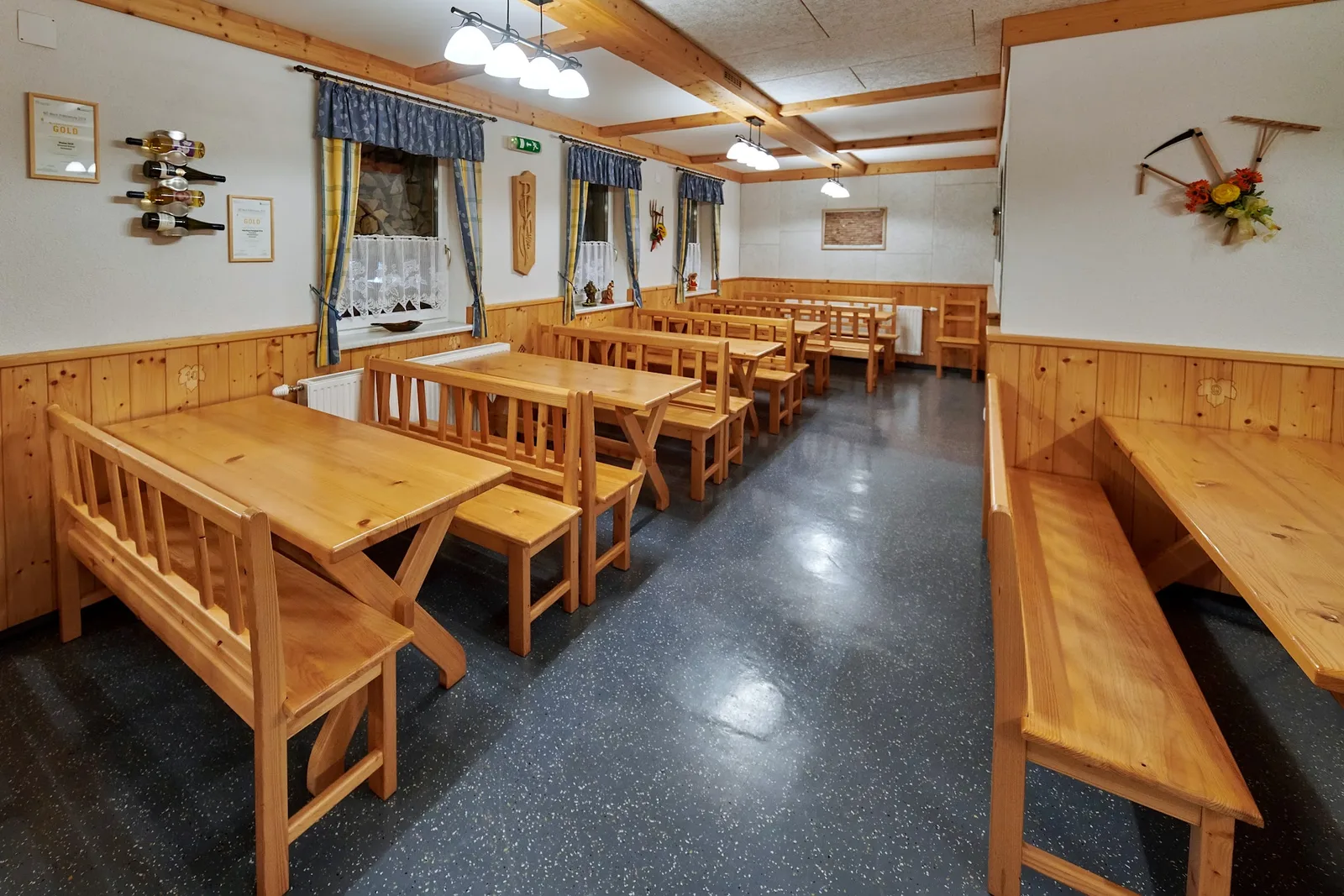 Heurigenstube mit langen Holztischen, Bänken und gerahmten Urkunden an der Wand