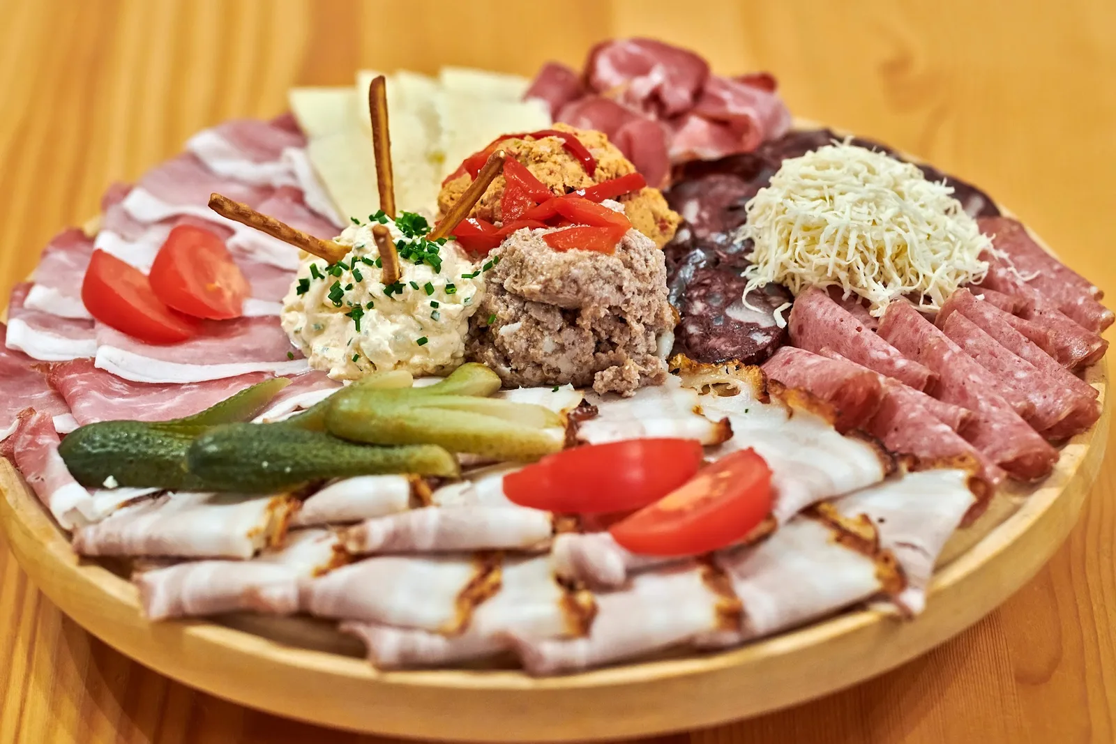 Winzerplatte mit Aufschnitt, Käse, Aufstrichen, Essiggurken und Tomaten auf einem Holzbrett